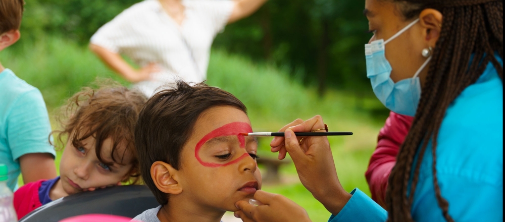 Enfant se faisant maquiller lors d'un événement par une animatrice Histoire de fêtes