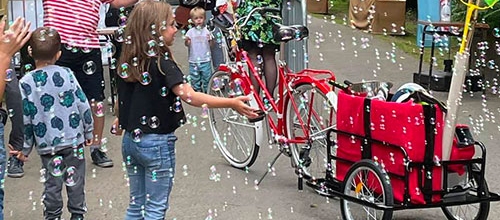 Enfants entourés de bulles de savon produites par un cyclo-bulles