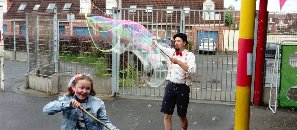 Animateur d'Histoire de fêtes formant une bulle géante avec un cyclo-bulles devant une petite fille