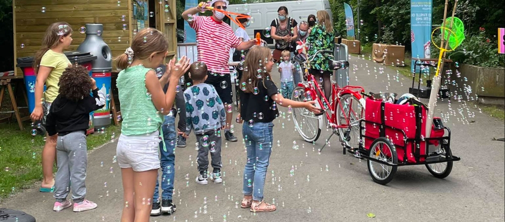 Animateur présentant l'animation cyclo-bulles à des enfants au milieu des bulles de savon