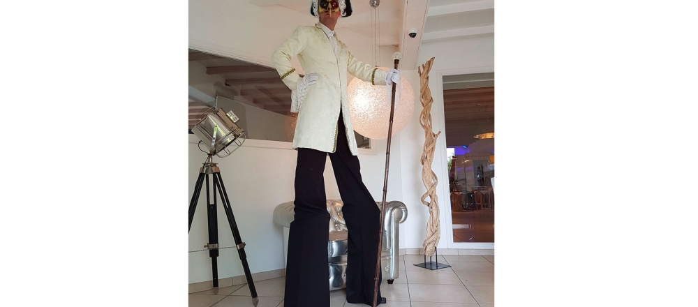 Acteur et animateur Histoire de fêtes monté sur ses échasses dans une galerie d'art